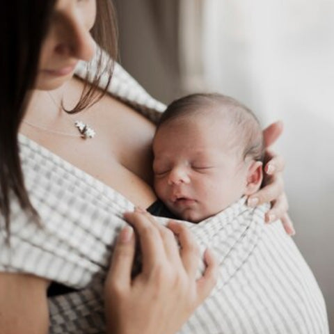 Maman porte bébé dans une écharpe de portage confortable